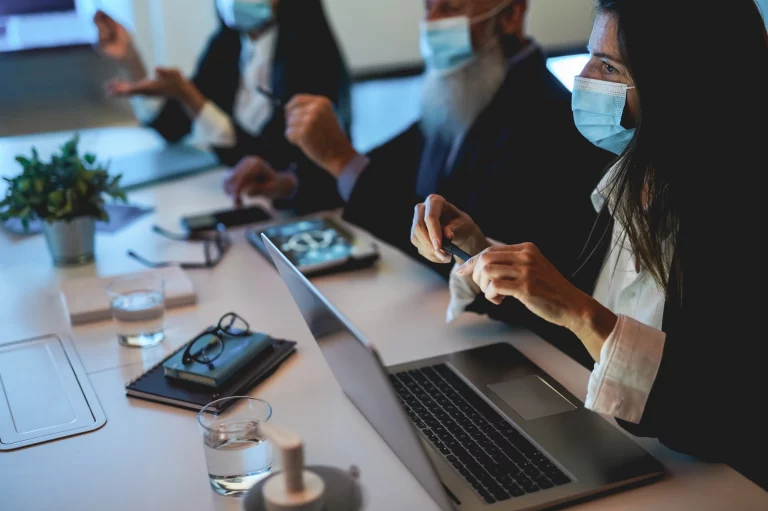 Business teamwork doing blockchain analysis inside fintech company office wearing safety mask